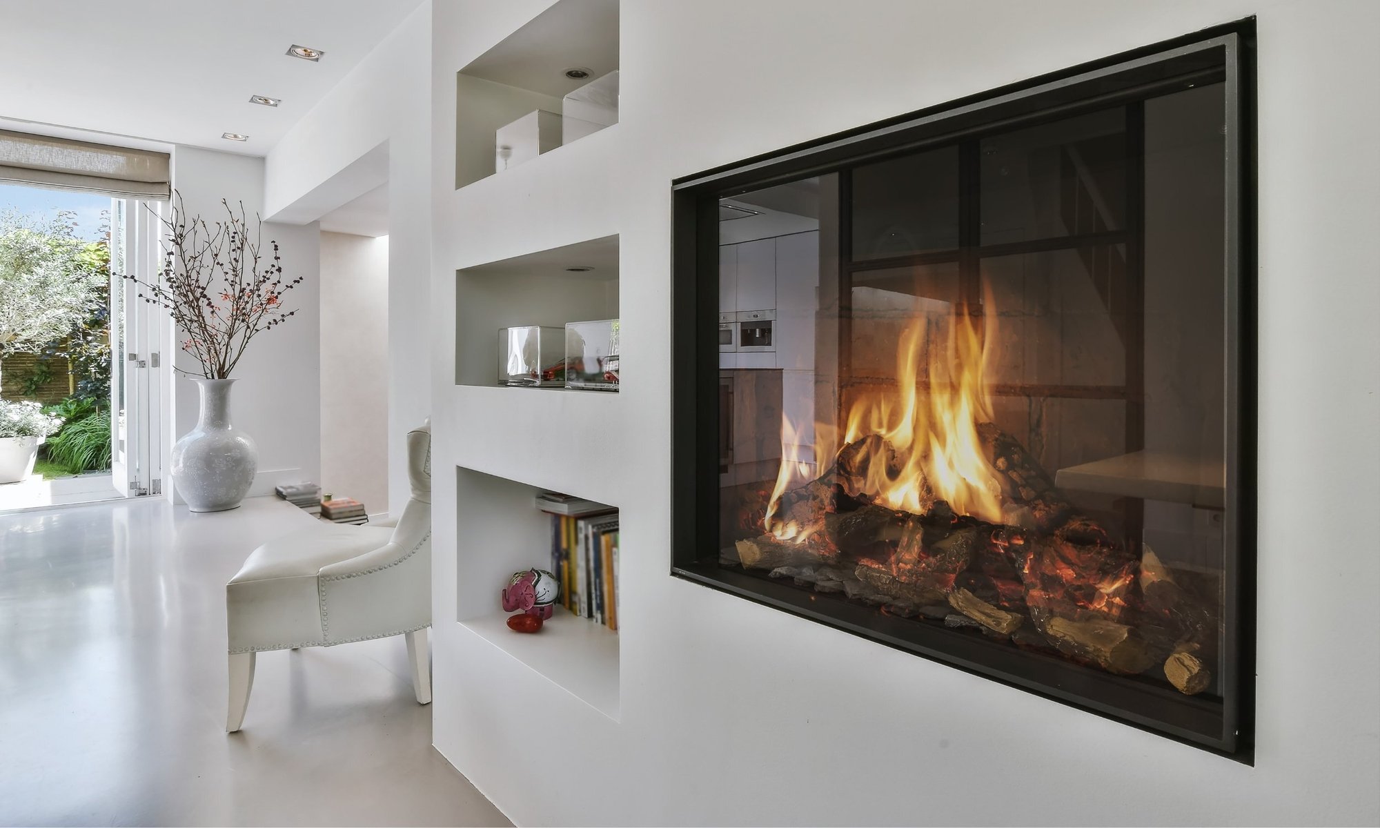 Modern linear gas fireplace built into a white wall with a black frame in a contemporary open-concept living space.