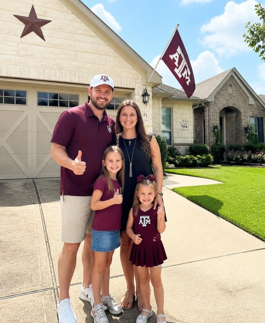 Family standing in front of a carriage-style garage door outside a residential home.