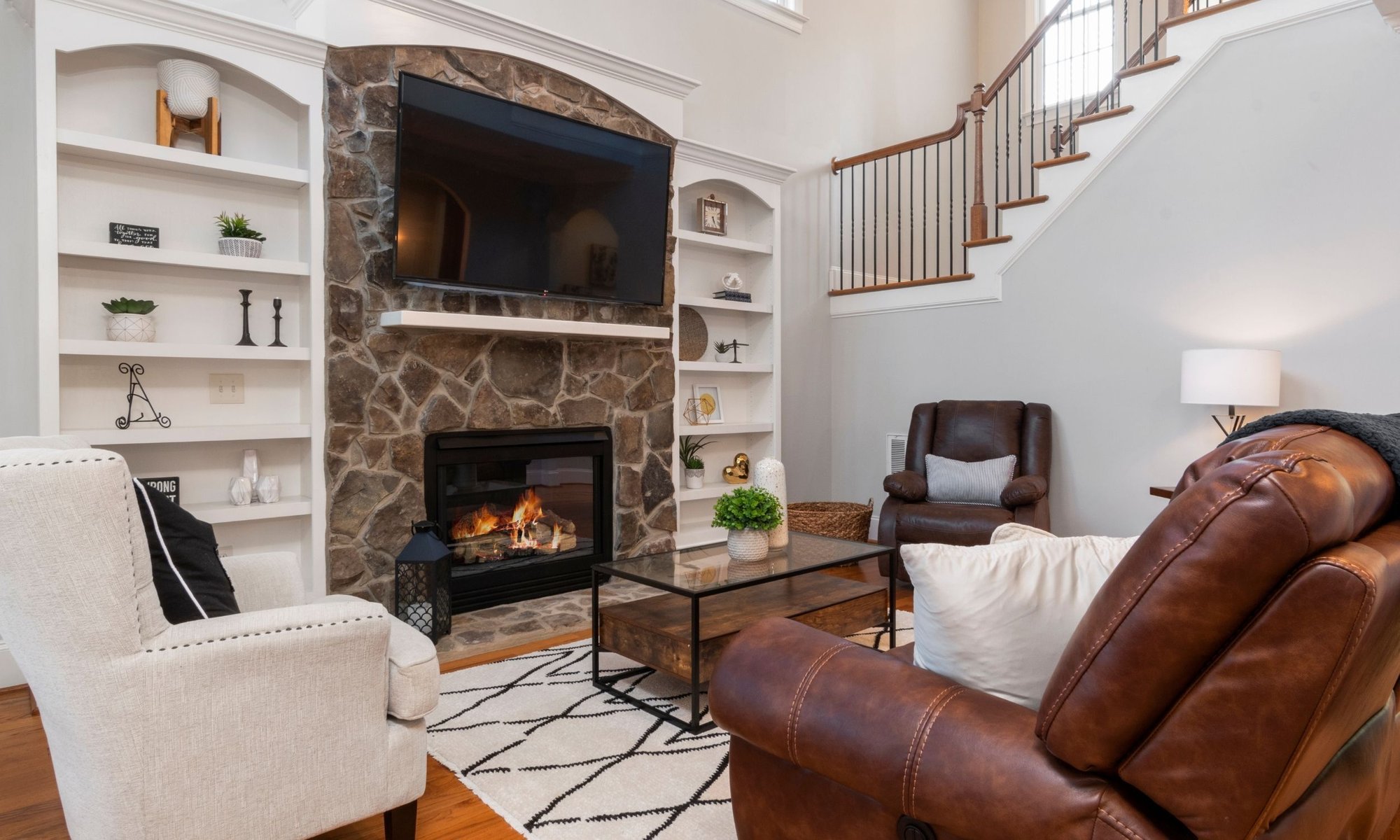 Contemporary living room with a floor-to-ceiling stone gas fireplace, mounted television, and built-in shelving.
