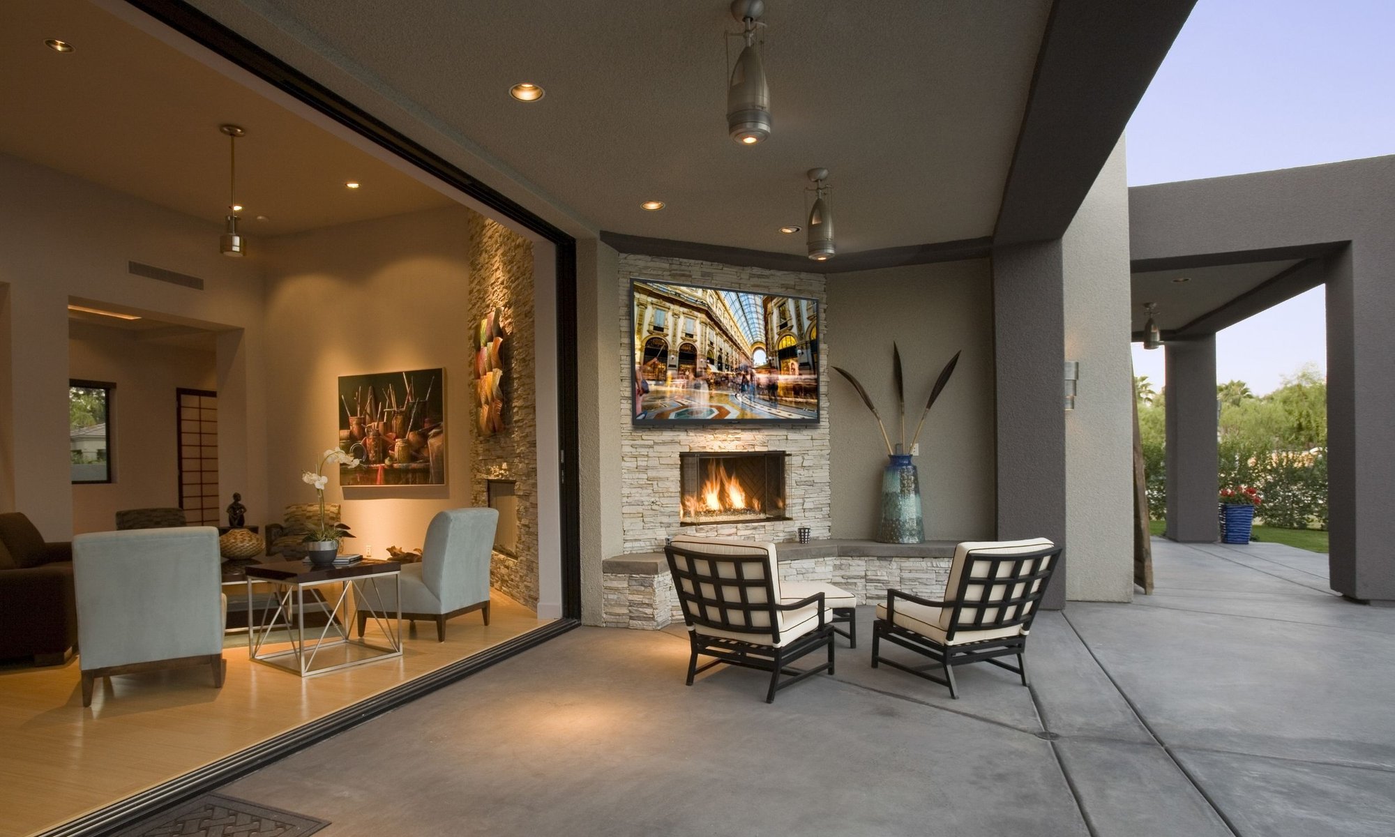 Modern outdoor living space with a covered patio, built-in gas fireplace, and seating area overlooking the backyard.